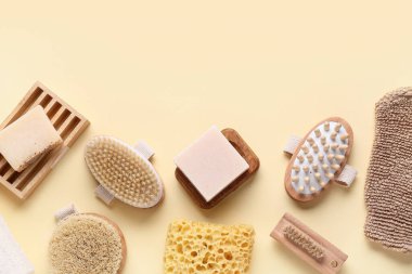 Bej arka planda masaj vücut fırçaları, sabun çubukları ve süngerlerle kompozisyon, yakın plan