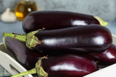 Mavi grunge arka planda taze patlıcanlı ahşap tepsi.