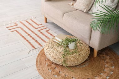 Havalı hasır puf çiçekli ve oturma odasında rahat bir kanepe.