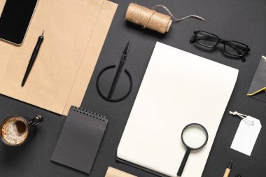 Cep telefonu, kahve fincanı, makas ve siyah arka planda teslimat kağıdı içeren kompozisyon