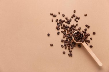 Bej arkaplanda kahve çekirdekleri olan tahta kaşık.