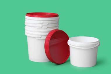 Yeşil arka planda bir sürü plastik boya kovası