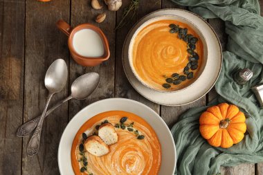 Tohumlu, kızarmış ekmek ve ahşap kaplama sarımsaklı balkabağı kremalı çorba kaseleri.