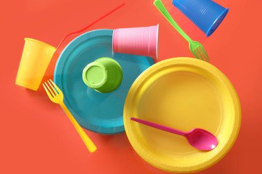 Kırmızı arkaplanda renkli plastik sofra takımı yükseliyor