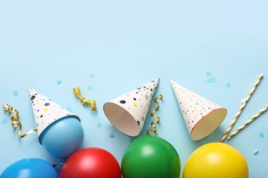 Mavi arka planda parti şapkaları, balonlar ve konfetilerle doğum günü kompozisyonu