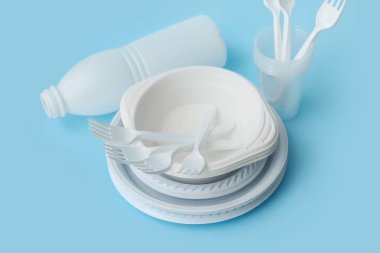 Açık mavi arkaplanda beyaz plastik sofra takımı