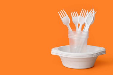 Turuncu arkaplanda beyaz plastik sofra takımı