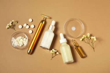 Kahverengi arka planda kozmetik ürünleri, haplar ve kolajen tozu şişeleri