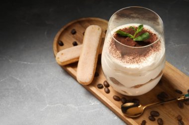 Tatlı tiramisu bardağı ve gri grunge arka plan malzemeleri, yakın plan.