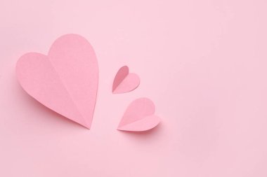 Pembe zemin üzerinde kağıt kalpler olan kompozisyon. Sevgililer Günü kutlaması