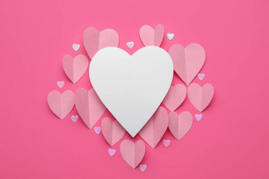 Pembe zemin üzerinde kağıt kalpler olan kompozisyon. Sevgililer Günü kutlaması