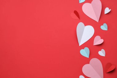 Kırmızı zemin üzerinde farklı kağıt kalpler olan kompozisyon. Sevgililer Günü kutlaması