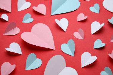 Kırmızı arka planda farklı kağıt kalpler olan kompozisyon, yakın plan. Sevgililer Günü kutlaması