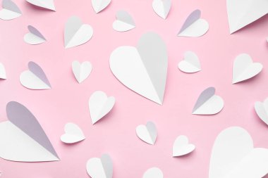Pembe zemin üzerinde beyaz kağıt kalpler olan kompozisyon. Sevgililer Günü kutlaması