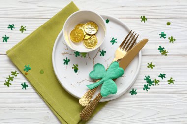 Aziz Patrick Günü kutlamaları için masa ayarlandı. Beyaz ahşap arka planda madeni paralar ve konfetilerle.