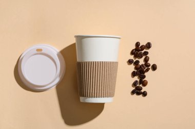 Kağıt bardak, kapak ve kahve çekirdekli kompozisyon bej arka planda, yakın plan