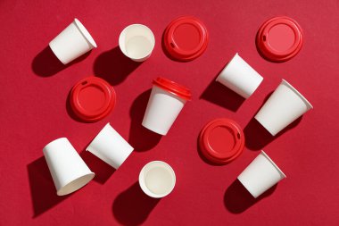 Kırmızı zemin üzerinde farklı kağıt bardaklar ve kapaklar olan kompozisyon