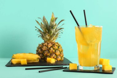 Turkuaz arka planda bir bardak taze ananas suyu.