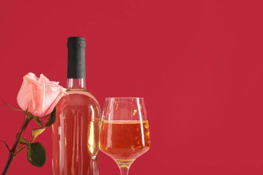 Kırmızı arka planda cam ve gül çiçekli bir şişe şarap. Sevgililer Günü kutlaması