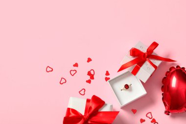 Nişan yüzüğü, hediye kutusu ve pembe arka planda hava balonu. Sevgililer Günü kutlaması