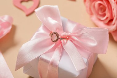 Nişan yüzüğü hediye kutusu ve bej arka planda gül çiçeği, yakın plan. Sevgililer Günü kutlaması