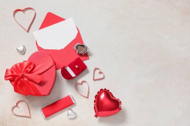 Zarflı nişan yüzüğü, boş kart, şekerler, hediye kutusu ve beyaz arka planda hava balonu. Sevgililer Günü kutlaması