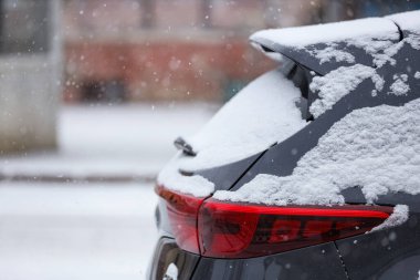 Kış günü şehirde karla kaplı modern siyah araba, yakın plan.