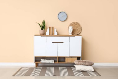 Odadaki bej duvarda kitap ve saat dolu çekmeceler.