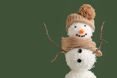 Yeşil arka planda şapkası ve eşarbı olan komik kardan adam.