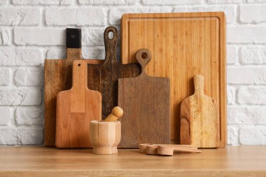 Tahta kesme tahtaları ve beyaz tuğla duvarın yanında tokmaklı havan topu.