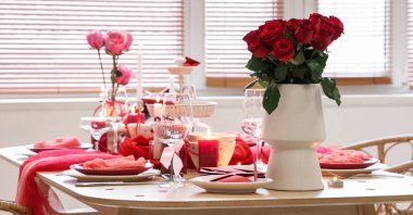 Kırmızı güller, yanan mumlar ve yemek odasında bardaklar. Sevgililer Günü kutlaması