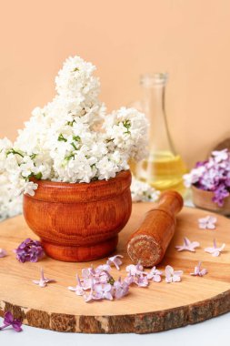 Turuncu duvarın yanındaki beyaz masada güzel leylak çiçekleri olan havan topu