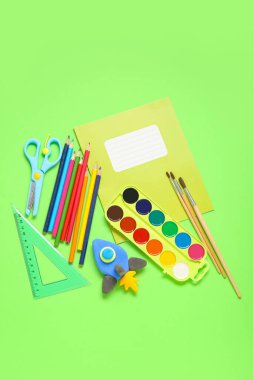 Yeşil arka planda farklı kırtasiye malzemeleriyle plastikten yapılmış roket