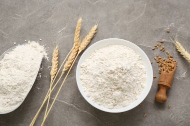 Gri masa üzerinde buğday unu ve çivili kase, yakın plan.