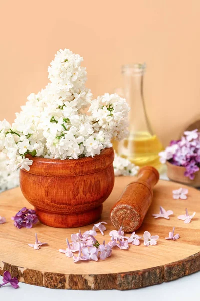 Turuncu duvarın yanındaki beyaz masada güzel leylak çiçekleri olan havan topu