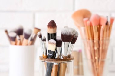 Beyaz tuğla arka planda makyaj fırçası olan tutucular