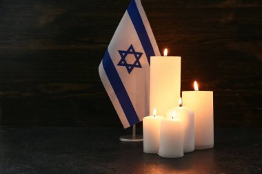 Ahşap arka planda İsrail bayrağıyla mum yakmak. Anma Günü