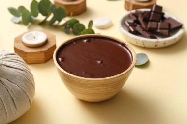 Soluk sarı arka planda erimiş çikolatalı spa kompozisyonu, yakın plan.