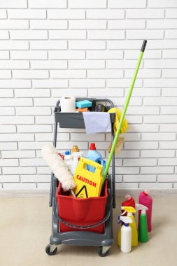 Beyaz tuğla duvarın yanında kapıcı arabası olan uyarı levhası.