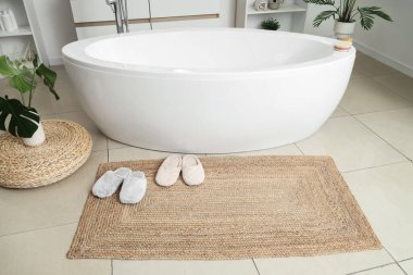 Banyo içinde hasır üzerinde terlikler.