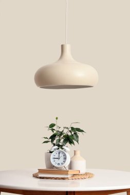 Masada kitaplar ve ışık duvarının yanında kolye bulunan çalar saat