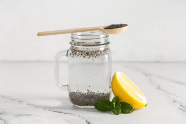 Beyaz grunge arka planında nane ve limon, chia tohumlu Mason kavanozu.