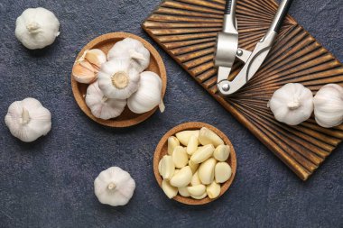 Koyu arkaplanda taze sarımsak ve tahta kaplar.