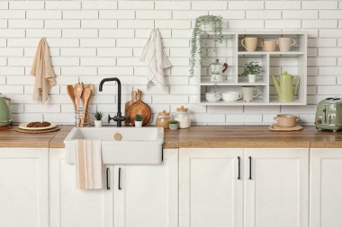 Beyaz tezgahlı, çatallı ve lavabolu şık bir mutfak.