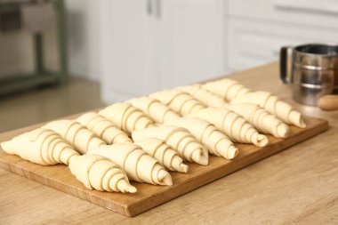 Mutfaktaki masada çiğ kruvasan olan ahşap tahta, yakın plan.