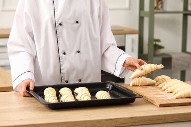 Baker mutfağa çiğ kruvasan koyuyor.