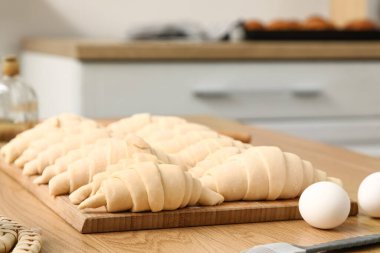 Mutfaktaki masada çiğ kruvasan olan ahşap tahta, yakın plan.