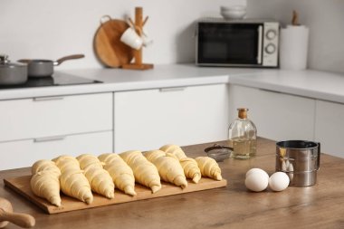 Mutfaktaki masada çiğ kruvasan olan ahşap tahta, yakın plan.