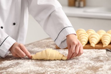Baker mutfaktaki masada çiğ kruvasan yapıyor, yakın plan.