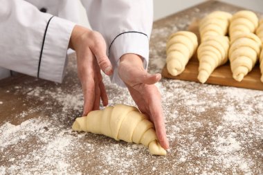 Baker mutfaktaki masada çiğ kruvasan yapıyor, yakın plan.